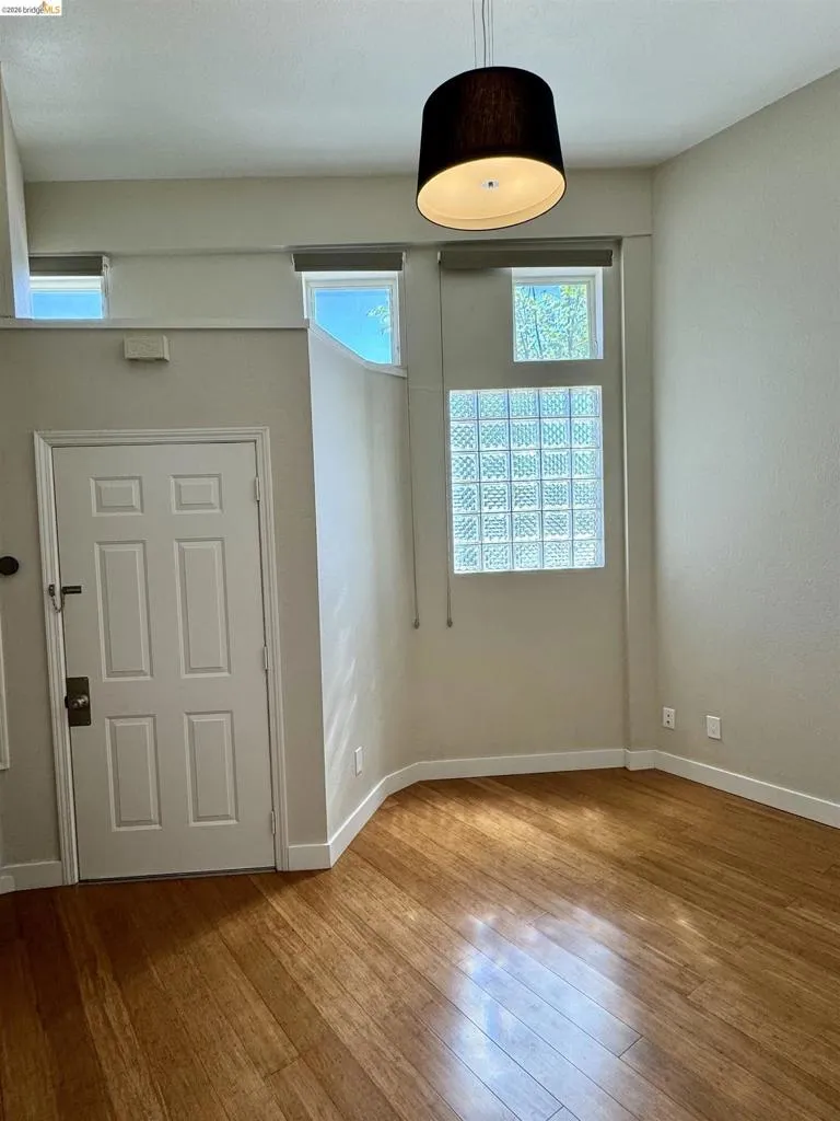 Empty room with hardwood / wood-style floors and healthy amount of natural light