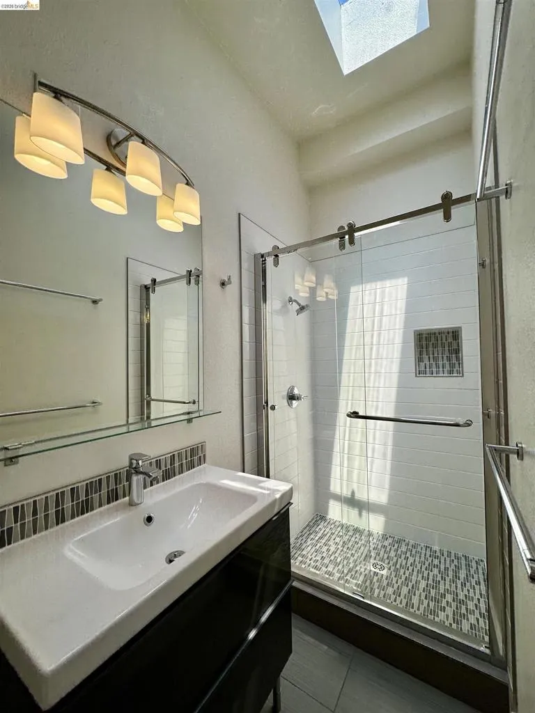 Full bathroom featuring vanity, a stall shower, and a skylight