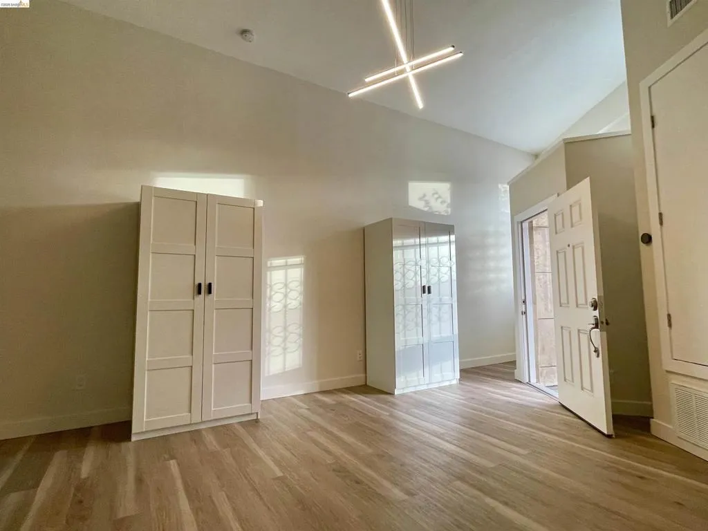 Unfurnished bedroom with light wood finished floors and lofted ceiling