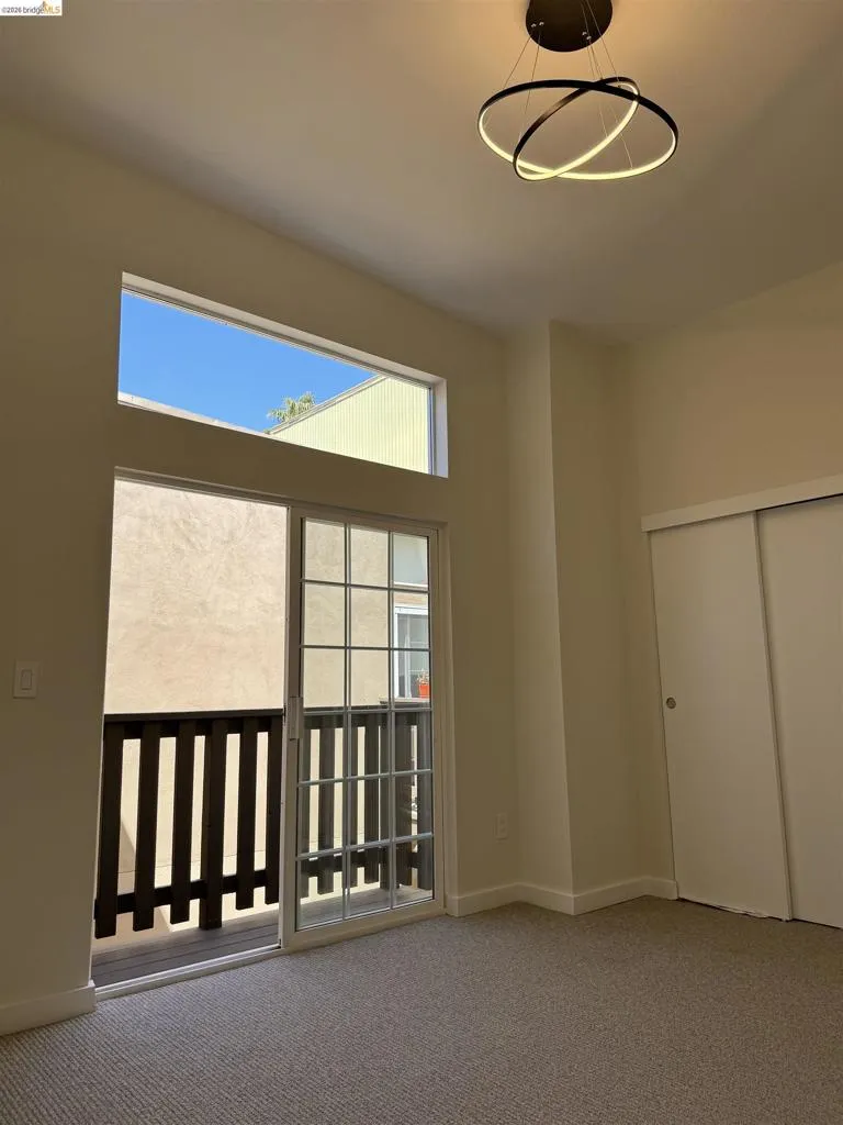 Carpeted empty room featuring a high ceiling and baseboards