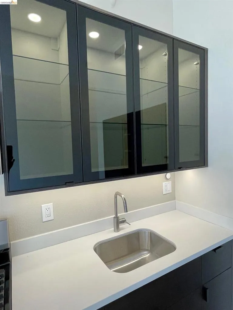 Bar featuring glass fronted cabinets and light stone counters