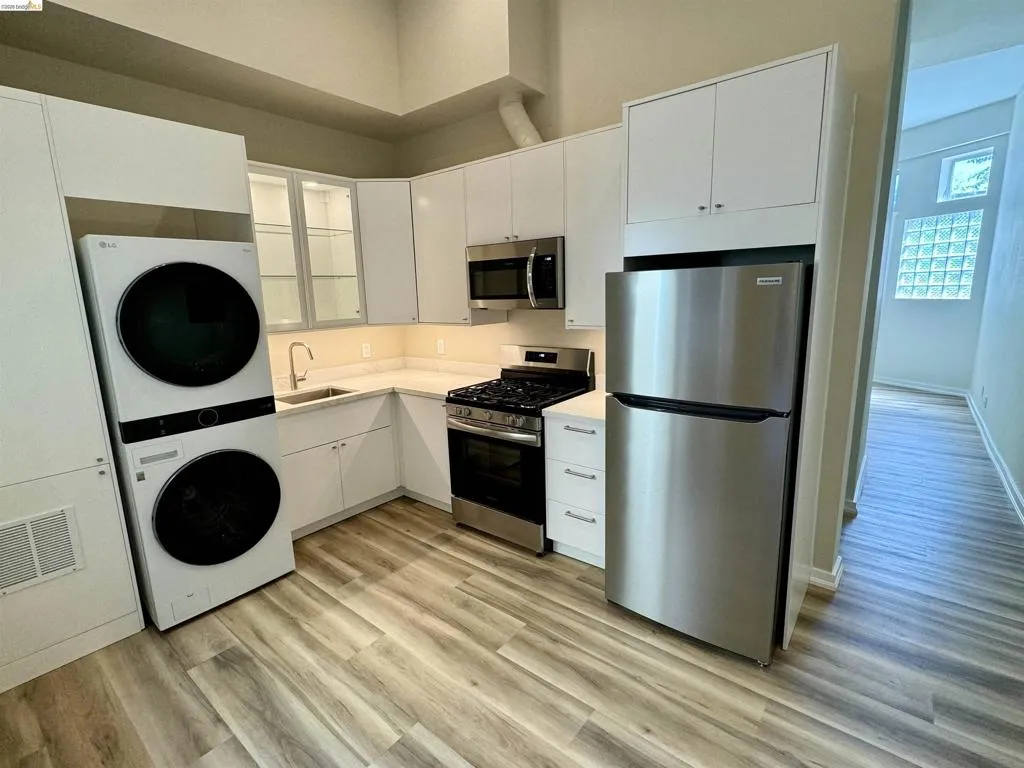 Kitchen with stainless steel appliances, light countertops, and white cabinetry