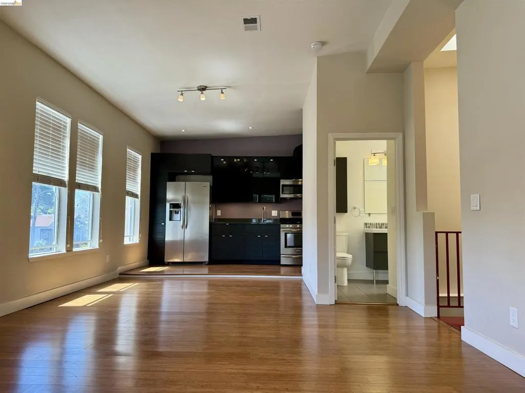 Unfurnished living room featuring dark wood-type flooring and baseboards