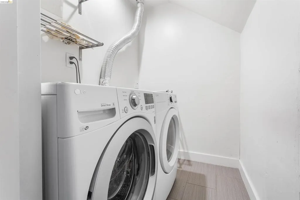 Laundry room featuring lofted ceiling and washer and clothes dryer
