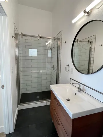 Bathroom featuring vanity, dark tile patterned flooring, and a stall shower