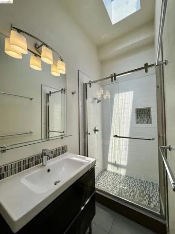 Full bathroom featuring vanity, a stall shower, and a skylight