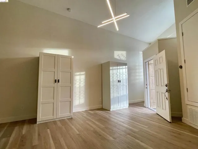 Unfurnished bedroom with light wood finished floors and lofted ceiling