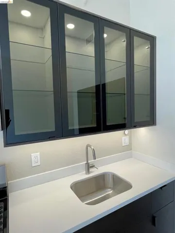 Bar featuring glass fronted cabinets and light stone counters