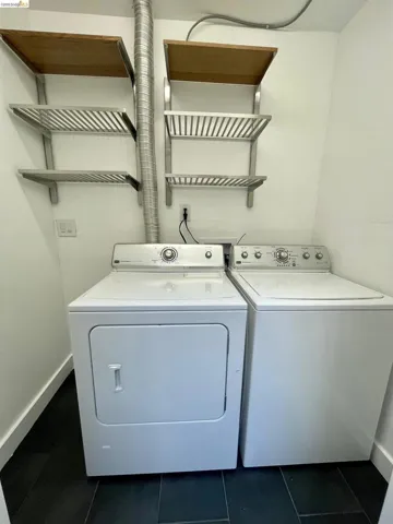Laundry area with separate washer and dryer and dark tile patterned floors