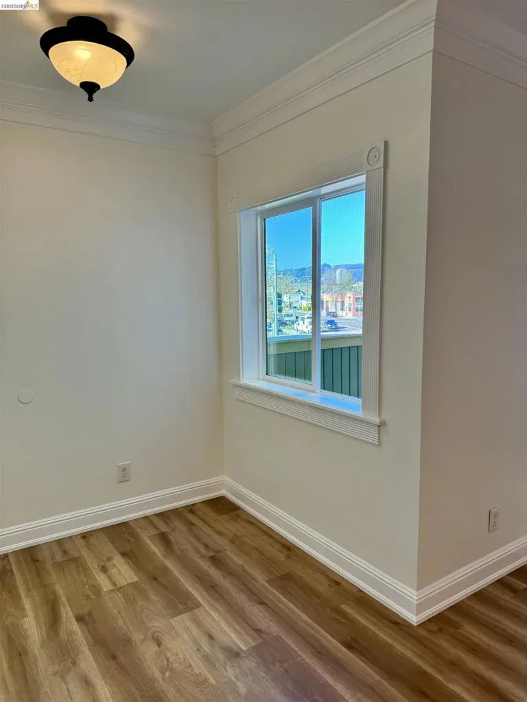 Empty room with light wood-type flooring and crown molding