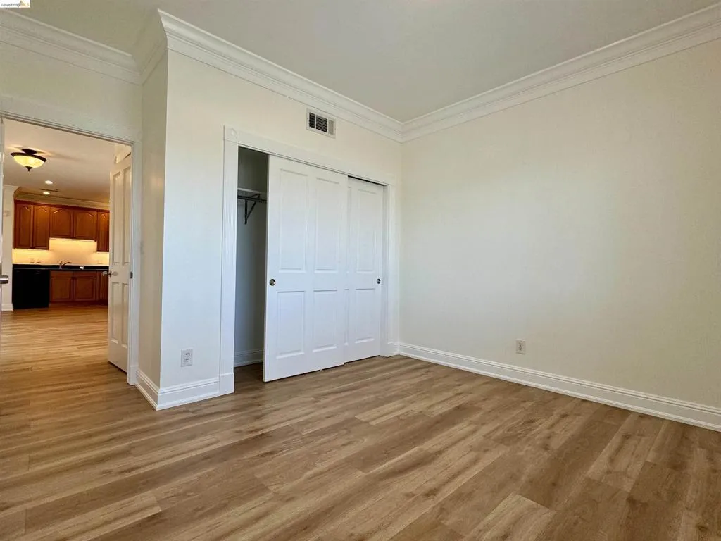 Unfurnished bedroom featuring crown molding, a closet, and light wood finished floors