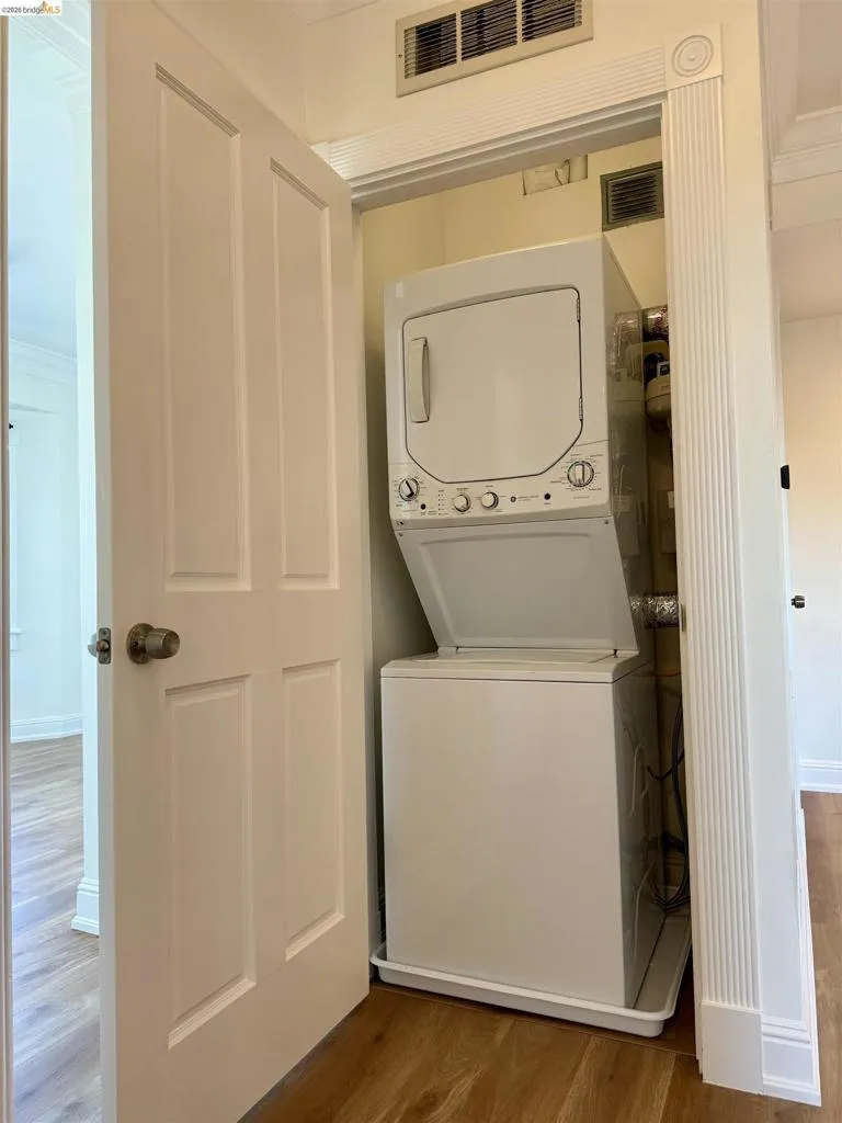 Laundry area with wood finished floors and stacked washer / drying machine