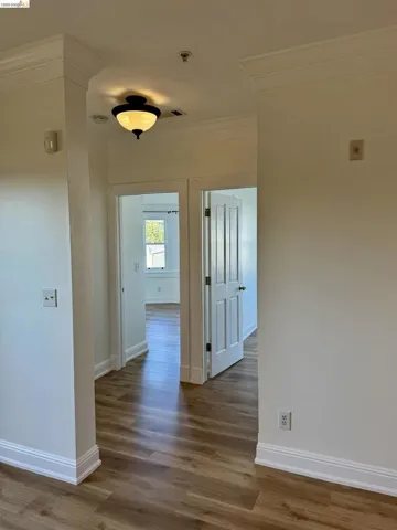 Hallway featuring ornamental molding and dark wood-type flooring