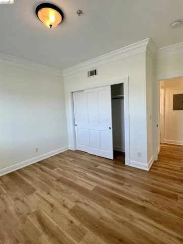 Unfurnished bedroom with ornamental molding, a closet, and wood finished floors