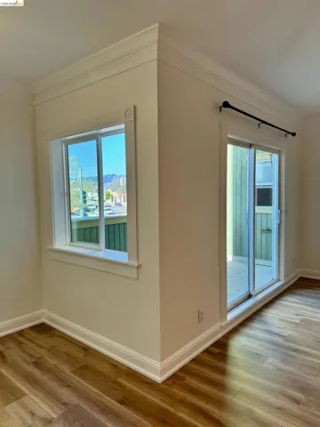 Spare room with crown molding, light wood-type flooring, and plenty of natural light