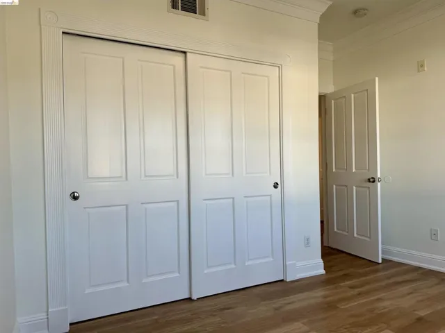 Unfurnished bedroom featuring a closet, crown molding, and dark wood-style flooring