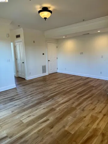 Empty room featuring dark wood-style floors and ornamental molding