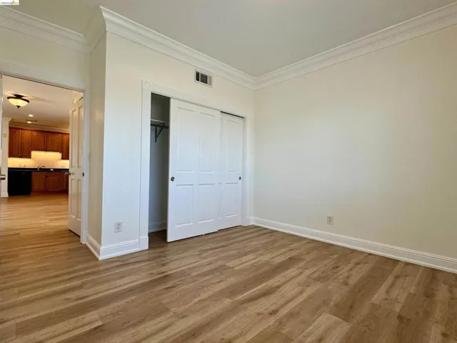 Unfurnished bedroom featuring crown molding, a closet, and light wood finished floors