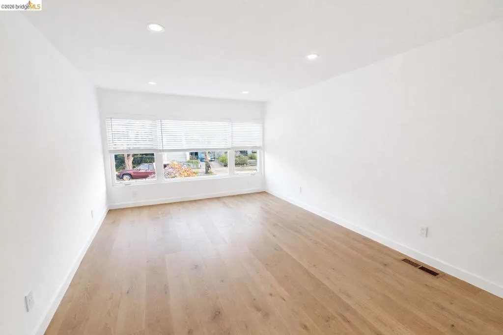Empty room with light wood-style flooring and recessed lighting