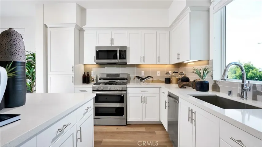 The kitchen includes quartz counters with a full height tile backsplash