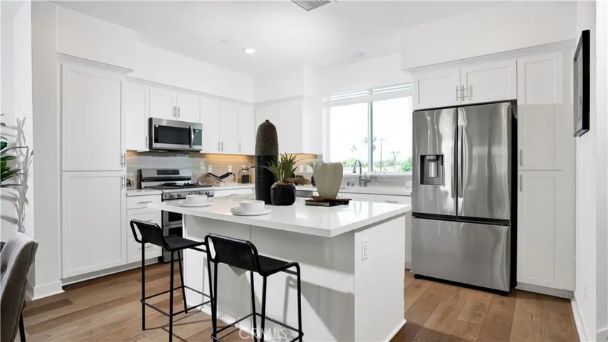 the kitchen features an island and stainless steel appliances, including this refrigerator