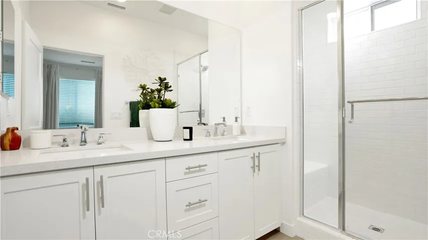 primary bathroom offers dual sinks and full height tile at the shower along with quartz counters.