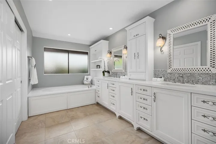 The primary bathroom showcasing the bathtub and remodeled dual vanity areas.