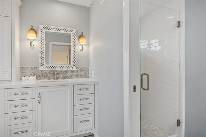 The primary bathroom shower to the right, showing one of the vanity areas on the left.