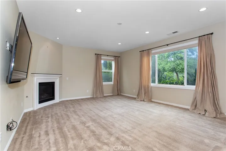 Family room w/ gas fireplace. All windows have upgraded electric shades via remote control for added privacy.