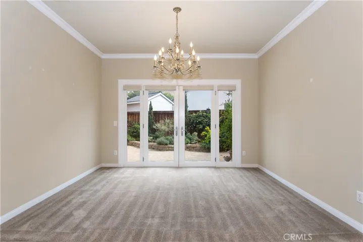 Dining Room w/ chandelier and upgraded French Doors to side yard. Upgraded electric shades with remote control for added privacy - all glass doors.