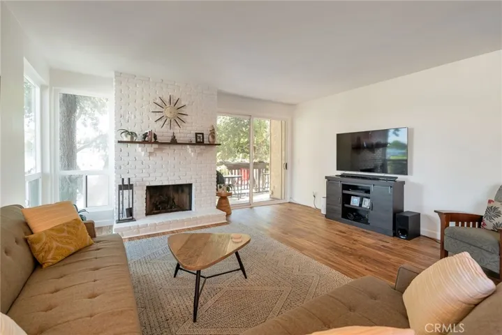 Large living room with beautiful views, natural light, brick fireplace and sliders to balcony