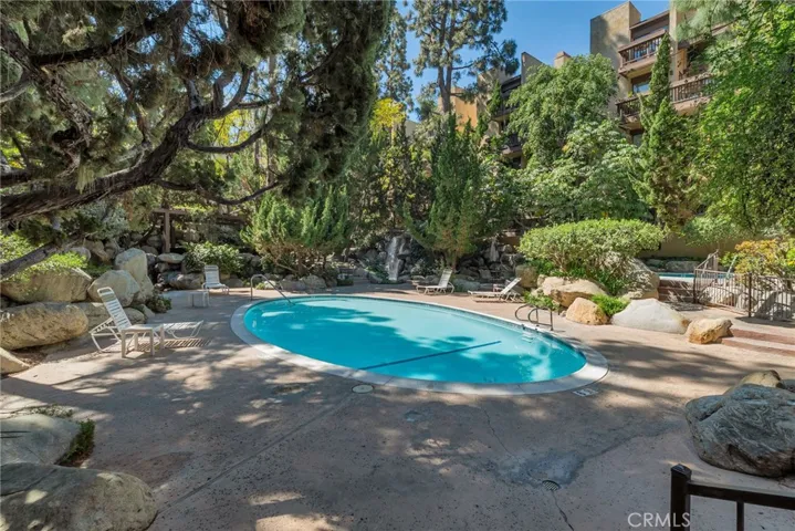 Resort-style pool surrounded by lush landscaping, tranquil water features, and serene lounge areas for ultimate relaxation