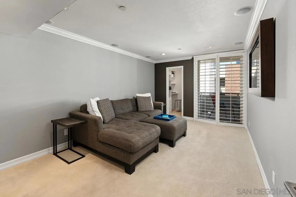 3rd bedroom is currently staged as a media/entertainment room.  Can also be used as a bedroom or exercise room.  Bedroom also has access to the balcony.  Note the plantation shutters and dual pane sliding door.