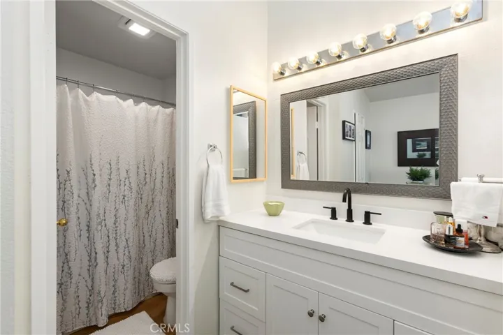 The primary bathroom with white cabinetry and quarts counters, and a tub/shower combination.