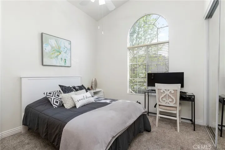 The secondary bedroom with high ceilings and a ceiling fan