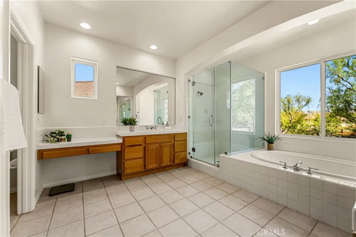 HIS AND HERS VANITIES WITH GLASS SHOWER ENCLOSURE AND SOAKING TUB