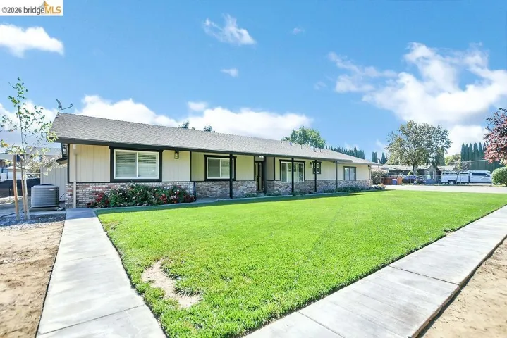 Ranch-style home with a front lawn, covered porch, and a shingled roof