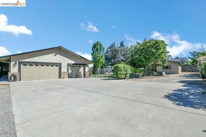 Ranch-style home featuring brick siding, driveway, stucco siding, an attached garage, and a gate