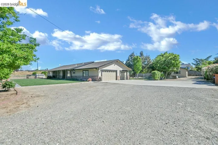 Single story home featuring concrete driveway, a garage, and stone siding