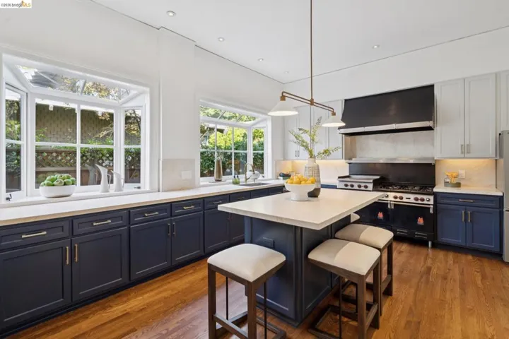 Two tone kitchen featuring backsplash, dark wood-style floors, a center island, a kitchen breakfast bar, and dual tone cabinets