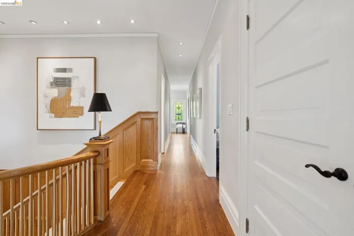 Corridor with ornamental molding, an upstairs landing, light wood-style flooring, wainscoting, and recessed lighting