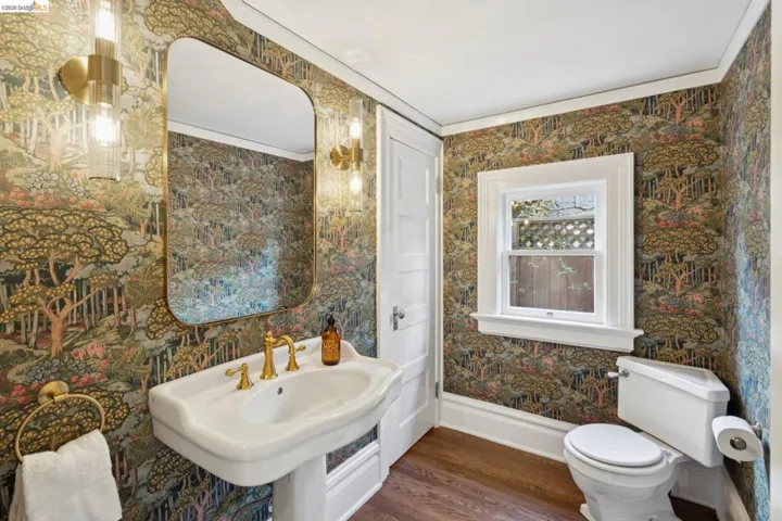 Bathroom with crown molding, dark wood-style floors, and wallpapered walls