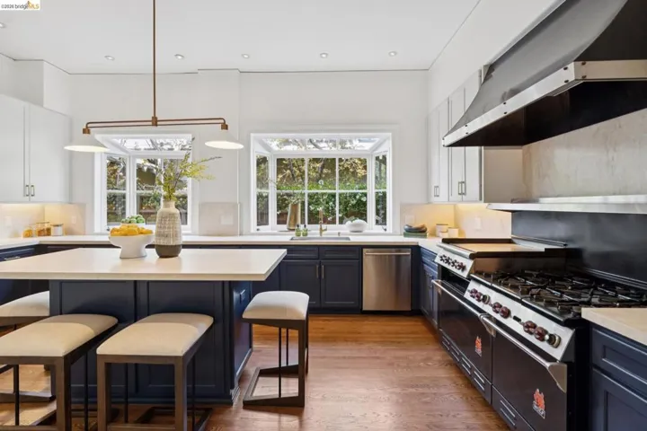 Kitchen with a breakfast bar area, tasteful backsplash, two tone cabinets, and light wood-style flooring