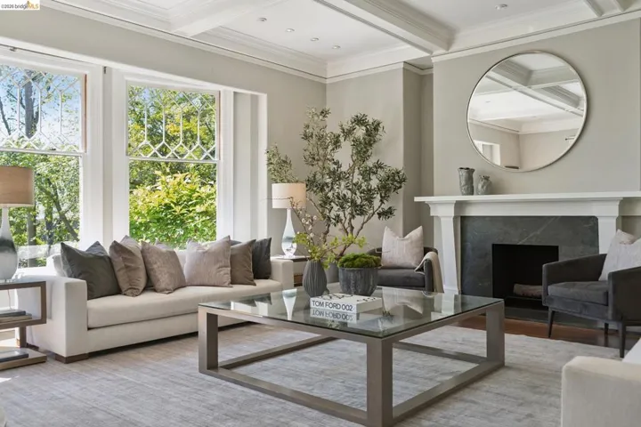 Living room with coffered ceiling, crown molding, a premium fireplace, and wood finished floors
