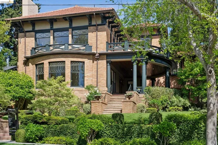 Rear view of house featuring brick siding, a chimney, and a balcony