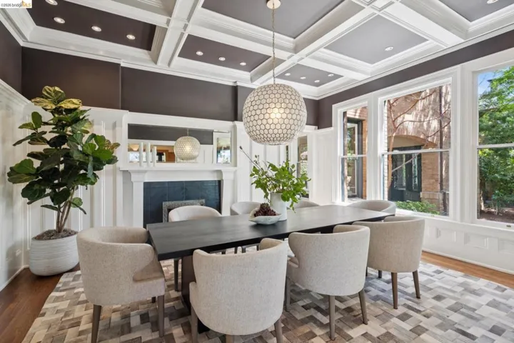 Dining room with wood finished floors, a fireplace, coffered ceiling, healthy amount of natural light, and ornamental molding