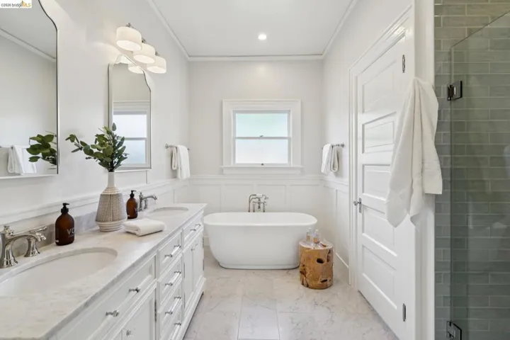 Full bathroom with crown molding, wainscoting, a shower stall, double vanity, and a freestanding bath