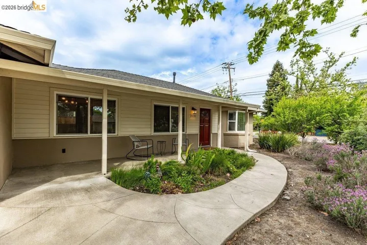 View of exterior entry featuring roof with shingles and covered porch
