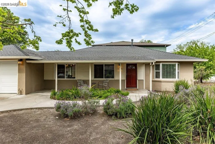 View of front facade featuring a garage, a shingled roof, stucco siding, concrete driveway, and covered porch