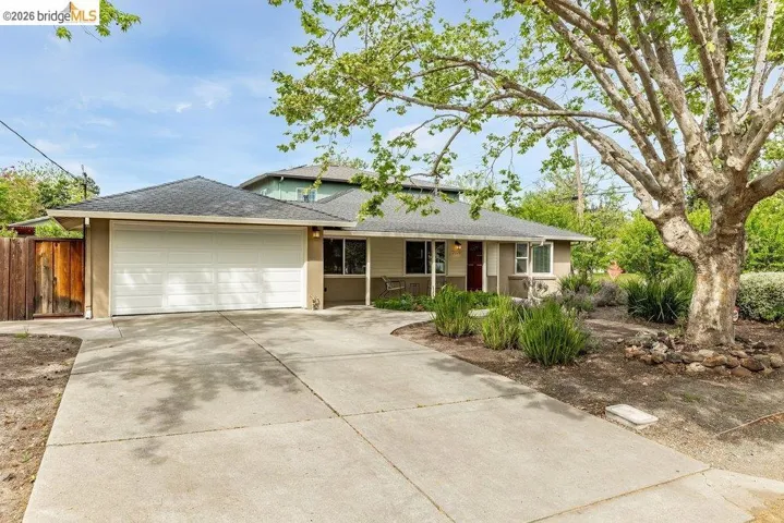 View of front facade with an attached garage, a shingled roof, concrete driveway, and stucco siding